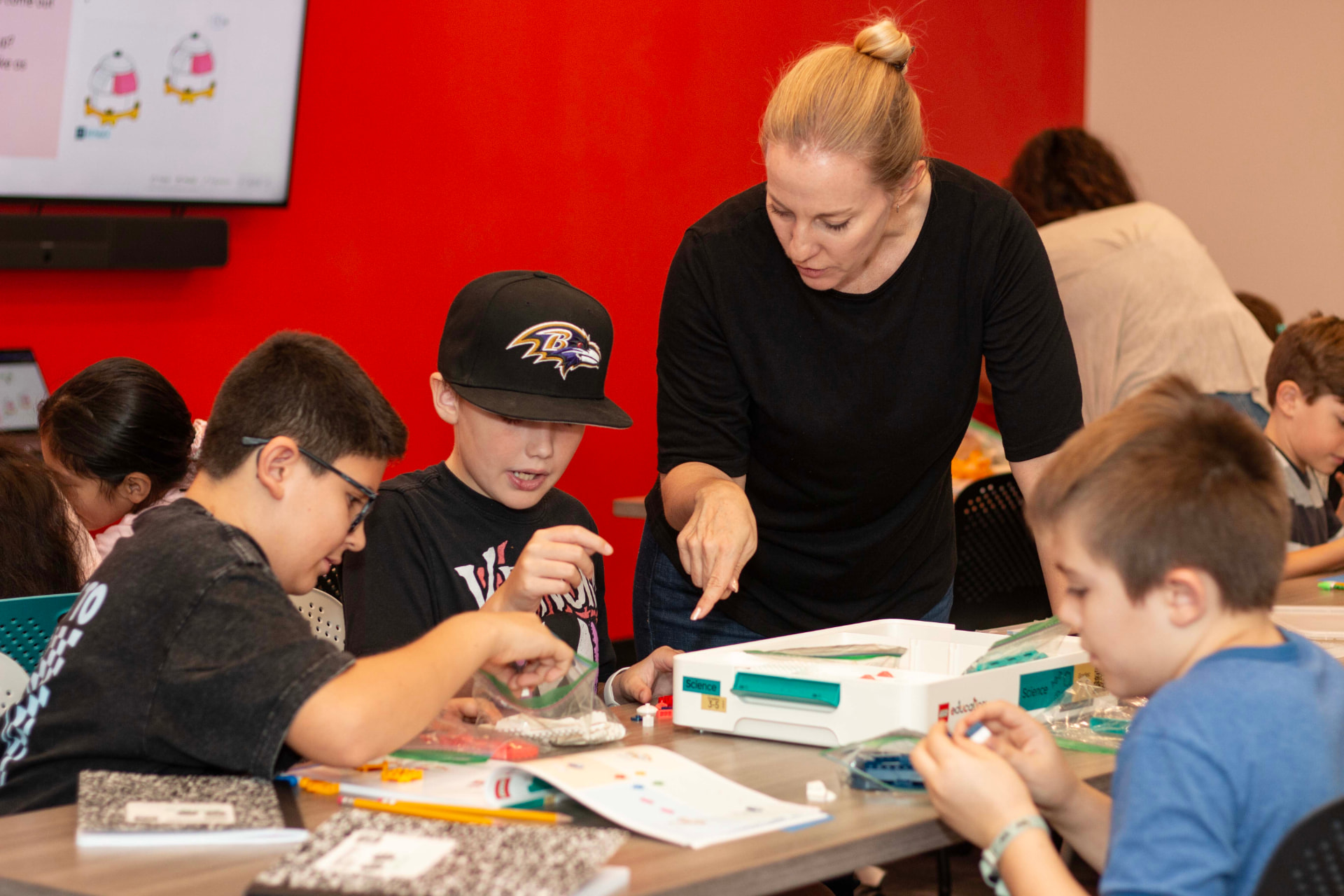 Teacher guiding two students through a LEGO science model