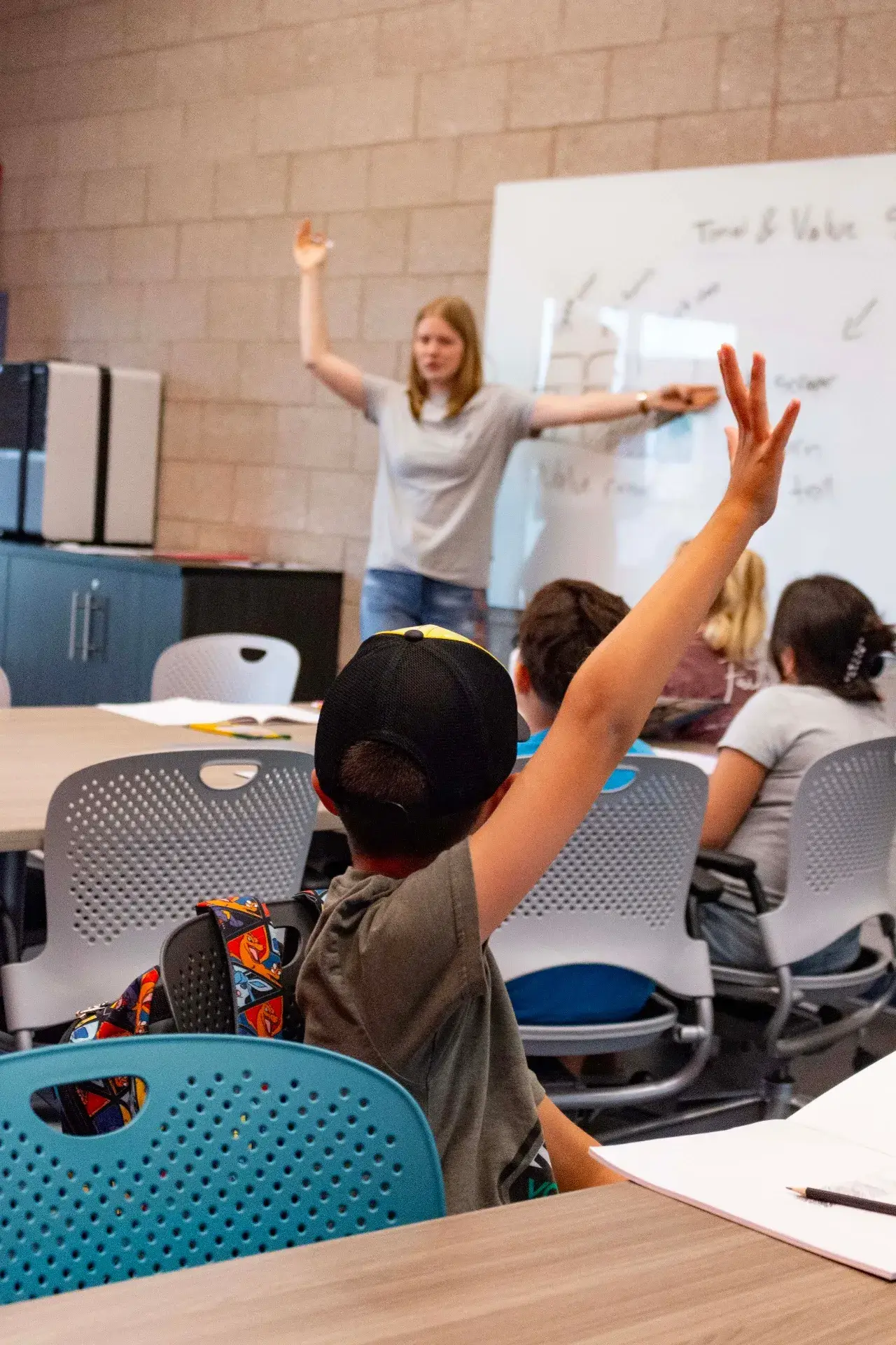 Child raising a hand during an art class