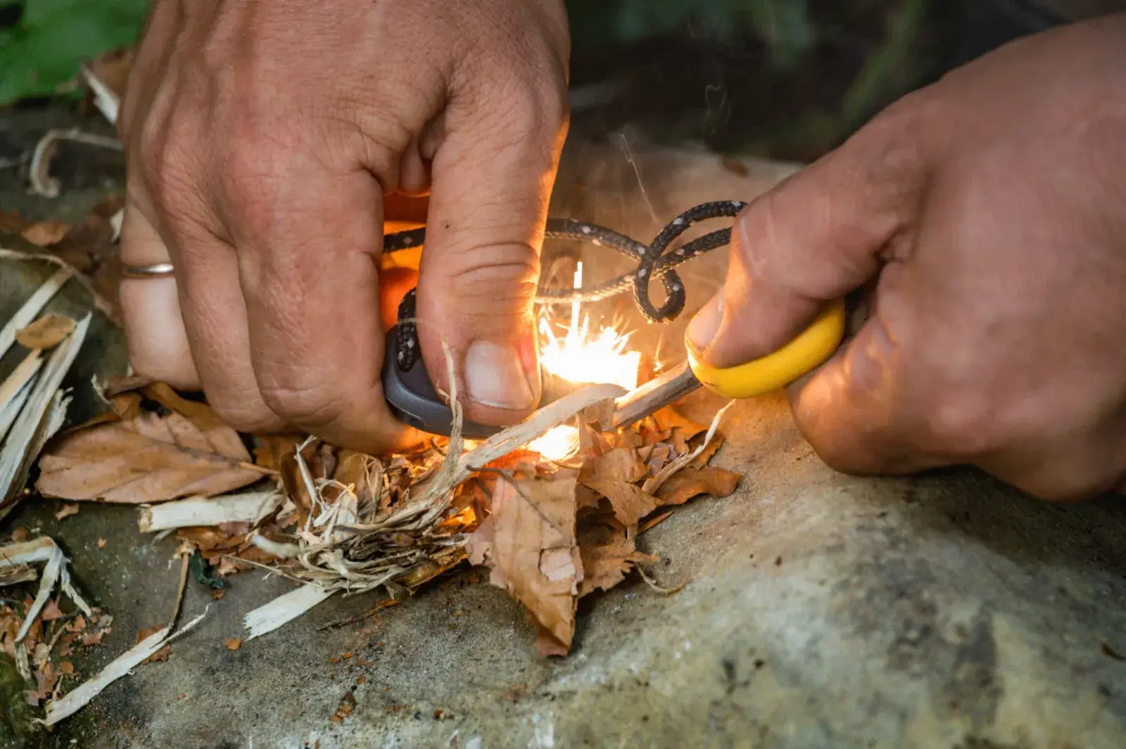 Hands starting a fire with a ferro rod